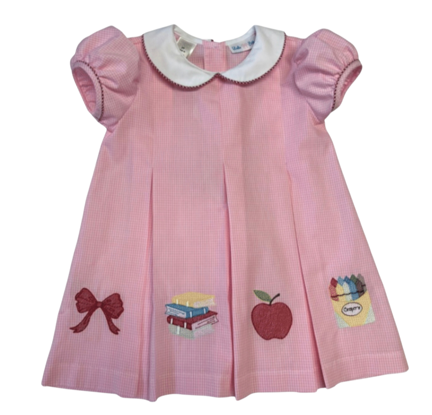 Pink dress with school apple appliqués on a white background
