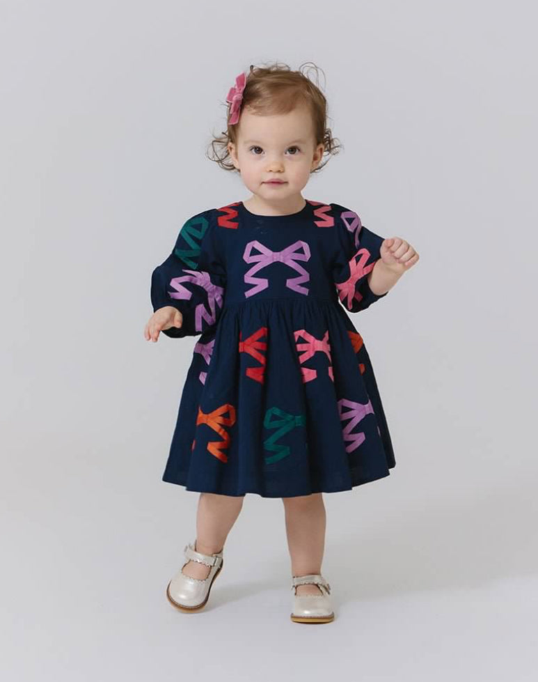 toddler girl wearing navy dress with colorful bows