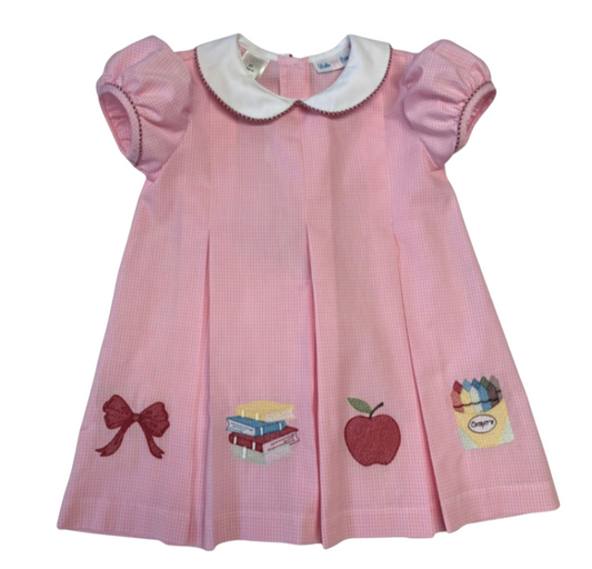 Pink dress with school apple appliqués on a white background